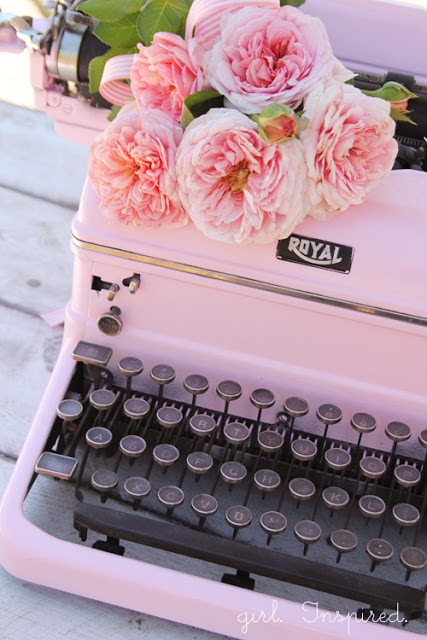 A light pink vintage typewriter decorated with faux peony flowers.