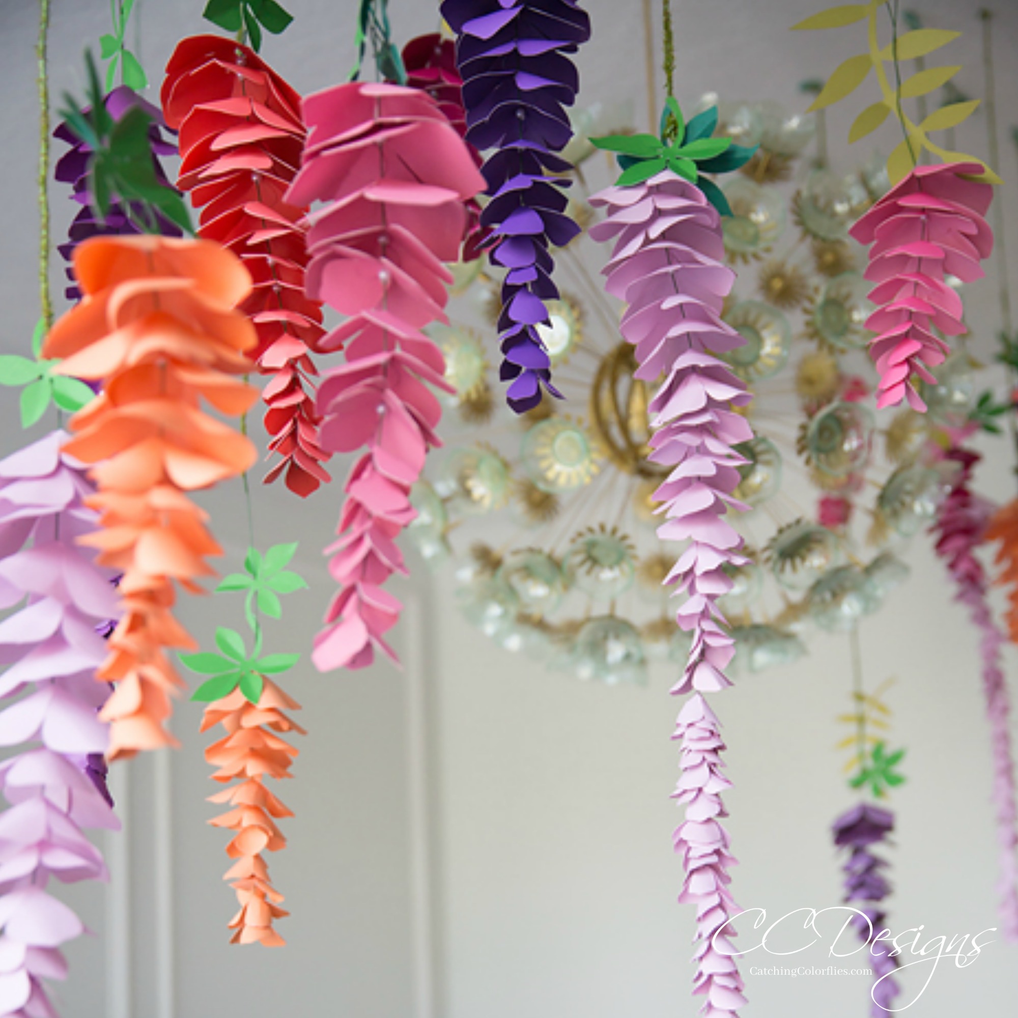 Paper wisteria flowers made from pink, purple, orange, and blue paper hangs from the ceiling.