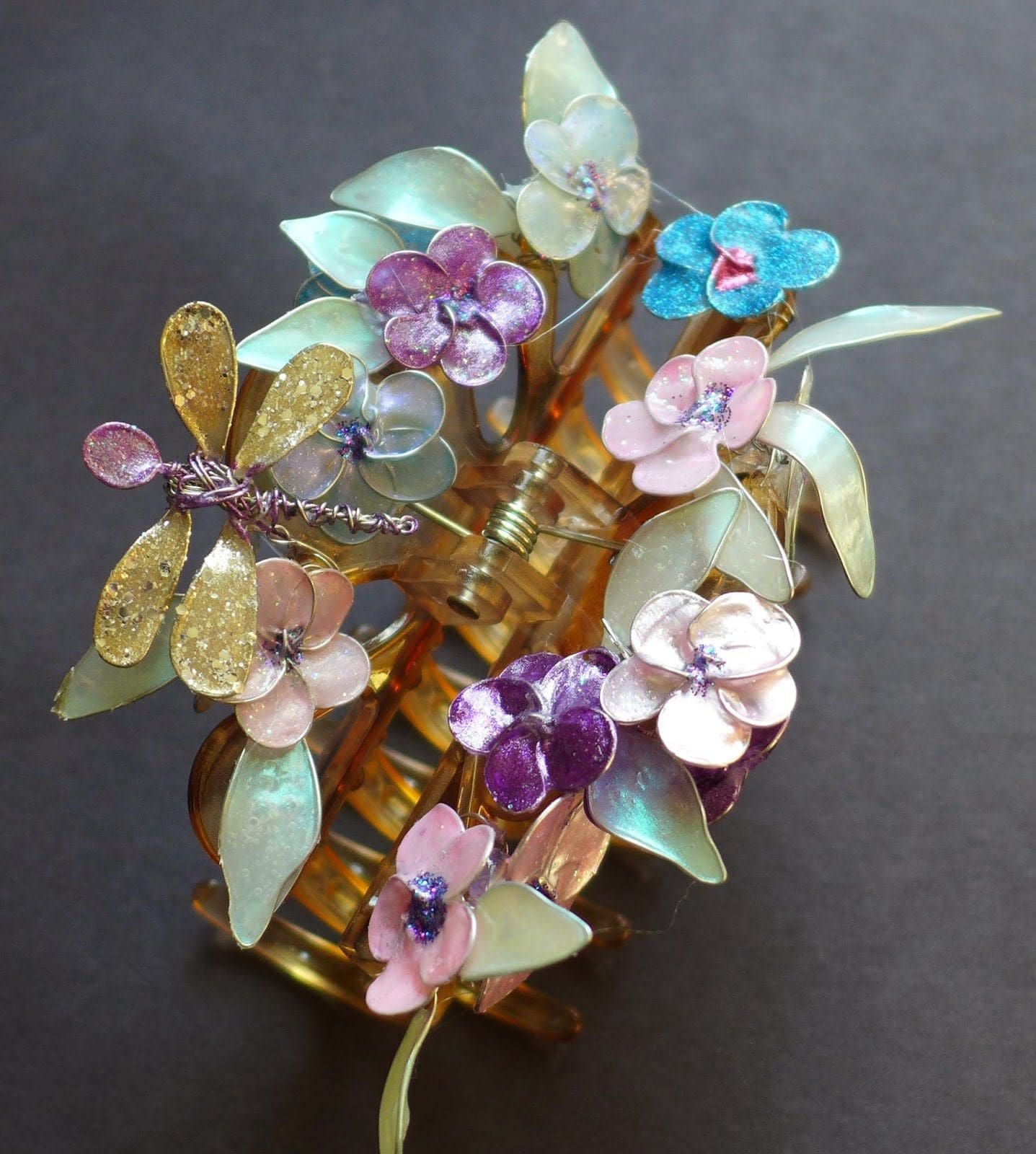 Dragonfly and flower wire jewelry pieces painted with pastel nail polish and attached to a brown hairlip. 