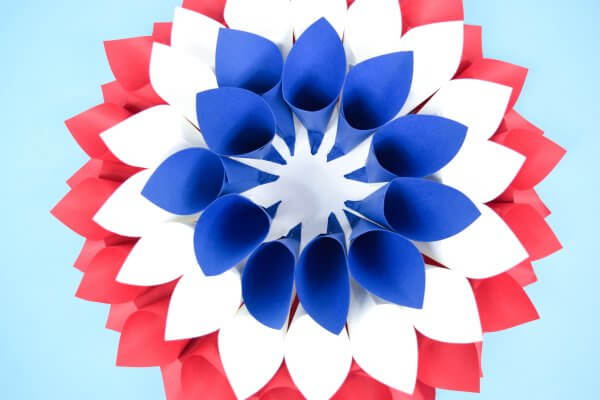 A layer of blue cones sits on top of the white cones, creating a 3D paper dahlia effect.