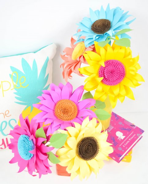 Colorful paper sunflowers made with pink, purple, yellow, and blue paper with pink, orange and brown sunflower centers.
