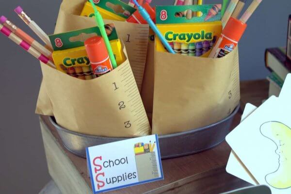 A back ot school welcome bag for students. School supplies like pencils, markers and glue sticks packed in brown paper bags.