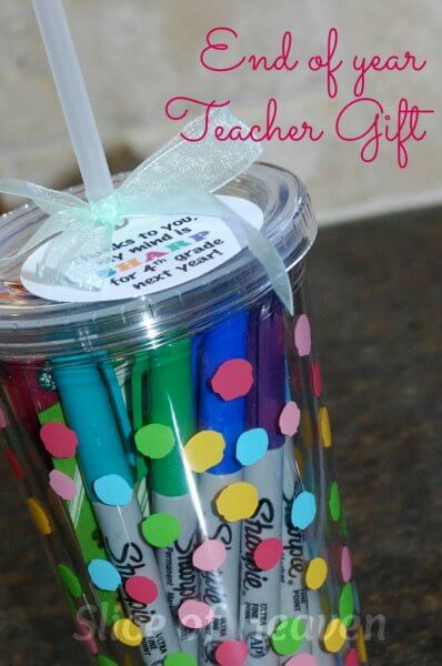 A plastic reusable tumbler decorated with polka dots and filled with Sharpie markers.