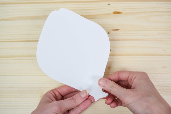 Hands forming the shape of a giant white paper petal.  