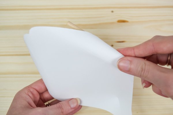A wooden dowel rolling the ends of a giant white paper petal. 
