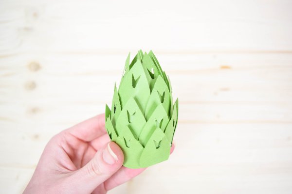 A hand holding a giant green paper stamen for a magnolia. 