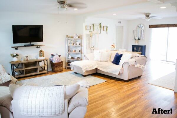 A combined living room and family room is bigger and still cozy with a focus on the color white and fully stuffed furniture. A TV hangs on the wall, and two large double doors to the outside bring in ample light. The word "After!" is typed in the lower right-hand corner. 