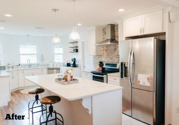 A renovated kitchen done in white colors with a marble counter island. Some counters and the sink have been moved into the in-kitchen dining space giving the kitchen more room and light. The word "After" is written in the lower left corner. 