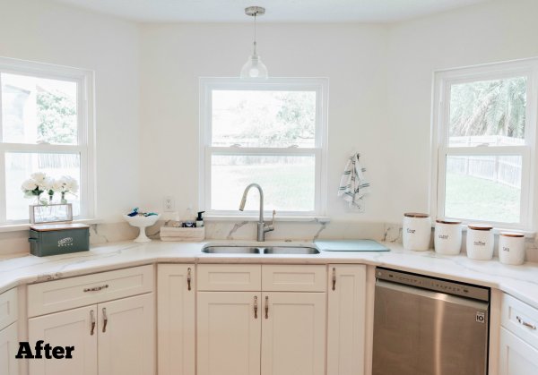 The half-octagon shape of this new kitchen now holds angled counters, shiny stainless steel appliances and open white windows. "After" is written in black font in the left bottom corner. 