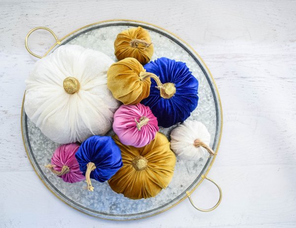 A collection of different size no-sew velvet pumpkins - gold, pink, white, and blue pumpkins on a crystal and gold platter.