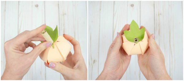 Two images showing the assembly of a stem into the paper pumpkin. 