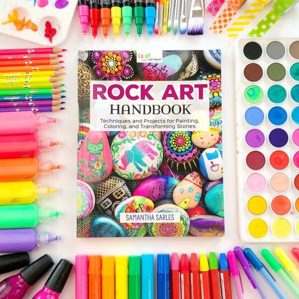 The Rock Art Handbook surrounded by colorful paints.