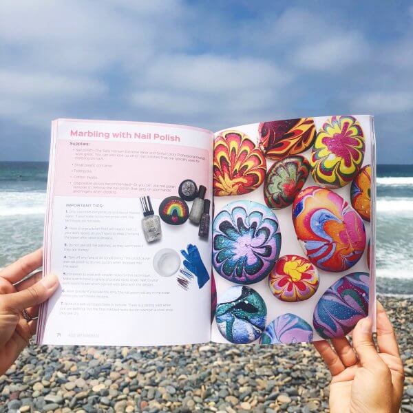 An open copy of the Rock Art Handbook with a rocky beach in the background. 