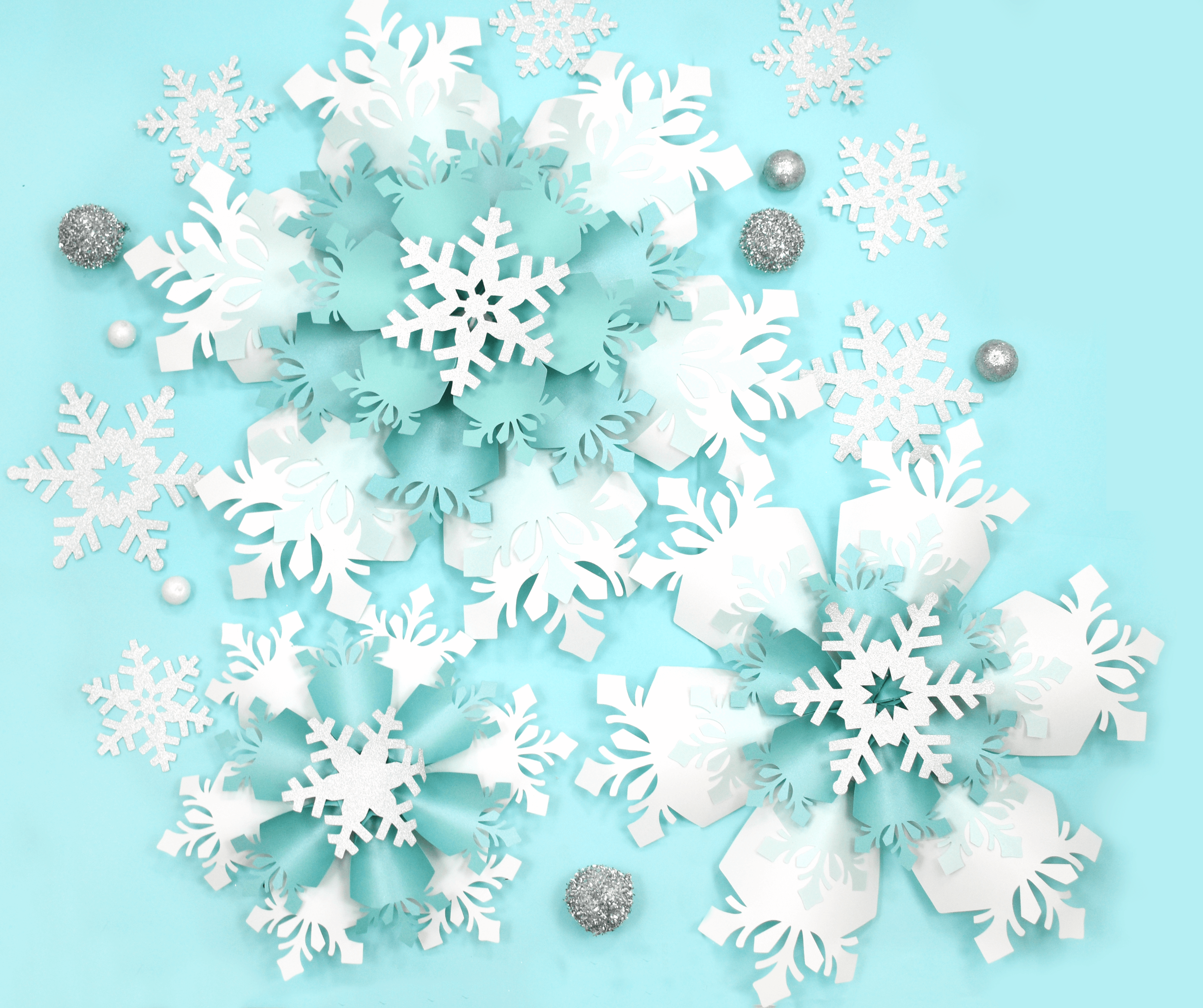 The image shows giant white and blue paper snowflakes made with Cricut. Get the templates on Abbi KIrsten Collections.