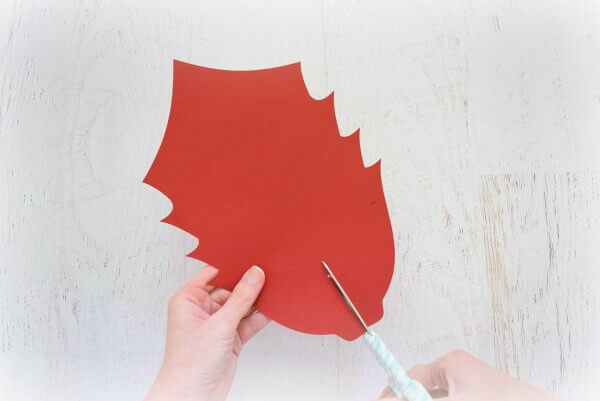 Abbi uses a scissors to cut a slit in the bottom of one large red poinsettia flower petal.
