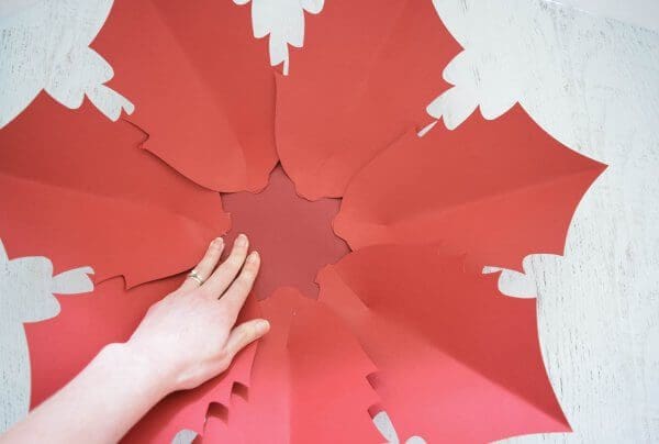 Seven large poinsettia flower leaves glued to a red base, making the base of a large Noel Poinsettia flower.