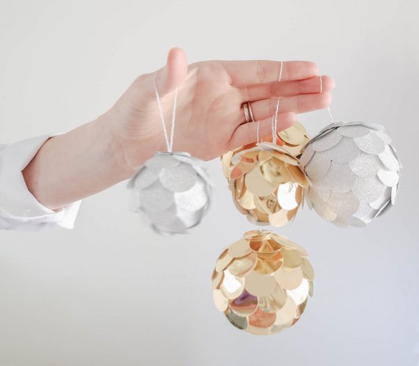Easy Christmas Ornament Crafts you can do with kids. Abbi Kirsten's arm extends outward with gold and silver circle ornaments hanging from her fingers. 