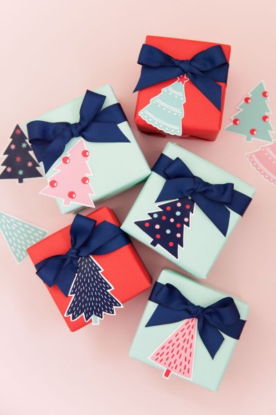 Five holiday gifts are wrapped with Tiffany blue and bright red wrapping paper, each accented with a navy blue ribbon bow and printable gift tags shaped like Christmas trees.