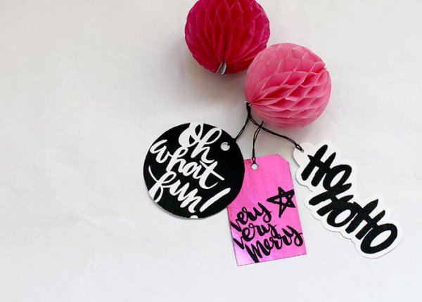 Small red and pink honeycomb balls are attached to black and pink glam and punk-rock gift tags. The tags say "Oh what fun," "very very merry," and "HoHoHo."