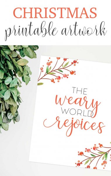 A Christmas card, made with a free SVG file from Abbi Kirsten, says "The weary world rejoices" on the card and "Christmas printable artwork" above the card, which is decorated with holly. 