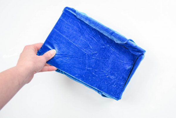 Chipboard, covered in blue velvet, is placed by Abbi Kirsten into a blue velvet fabric storage box. 