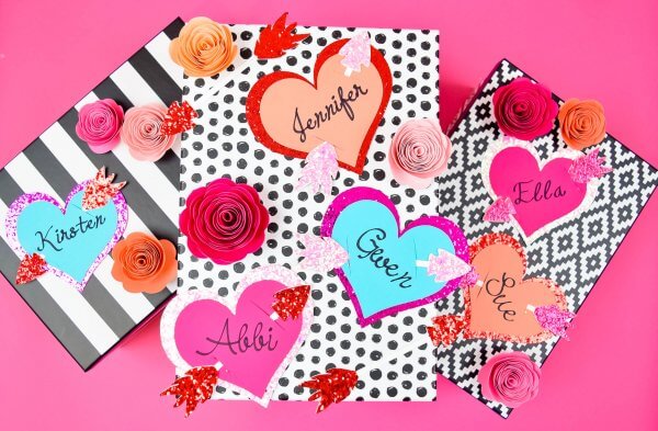Red, pink and blue personalized Valentine's Gift Tags along with paper flowers attached to black and white gift boxes.  