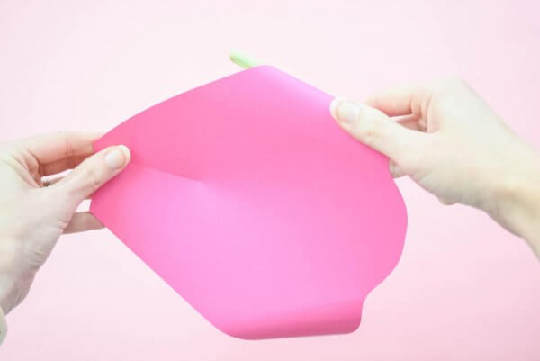 A close-up of Abbi Kirsten's hands as she uses a wooden dowl to curl back the top petal of the paper flower Penelope rose. 