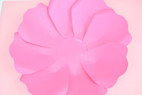 Making paper flowers begins with this finished bottom layer of pink paper petals. The petals are glued to a base and overlap counter-clockwise. 
