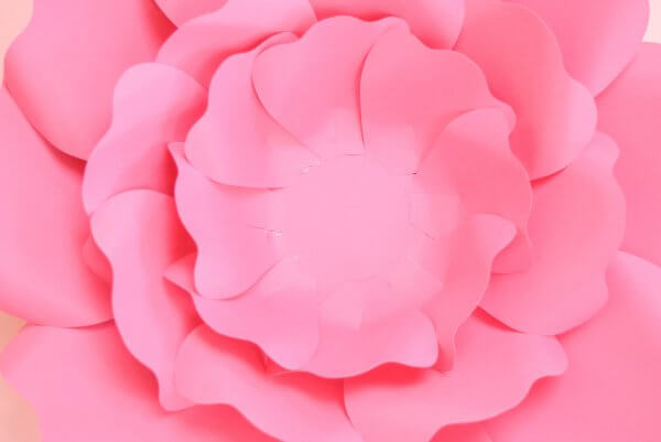 As part of a picture tutorial on making paper flowers, this overhead view of a Penelope rose shows the addition of a third layer of petals, sized medium. They overlap and alternate with the two pink layers underneath. 
