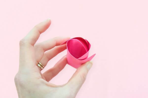 Abbi Kirsten's hand holds the beginning of a pink rosebud almost ready to be glued into the paper Penelope rose. 