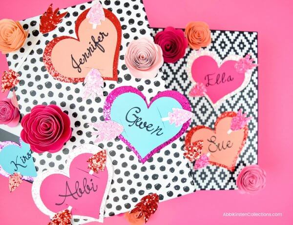 Personalized pink, red and blue heart and arrow Valentine's Gift Tags against a black and white graphic background.