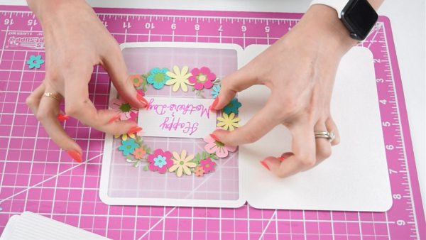 A pink Happy Mother's Day message placed in the middle of a floral wreath. 