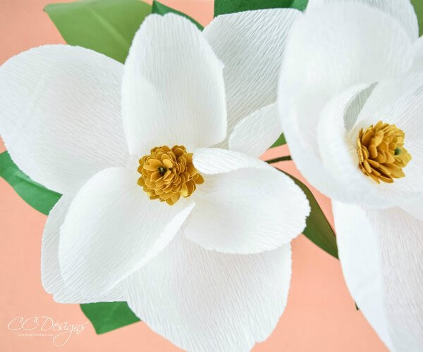 White magnolia crepe paper flowers with a golden-yellow flower center.