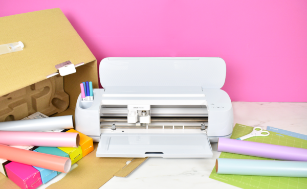 Cricut Maker 3 machine sitting on a craft desk with vinyl material and an open Cricut box. 