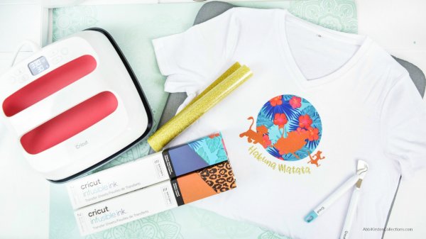 Cricut Infusible Ink cartons, a roll of gold glitter vinyl, an Easypress and a white t-shirt with "Hakuna Matata" written across and small African animals dancing in front of a blue floral pattern. Learn the top hacks for using vinyl with Cricut Infusible Ink. 