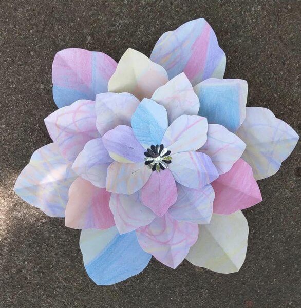 A photo of a white paper flower colored with watercolors. The photo is from one of Abbi Kirsten's followers, and shows that your imagination can run wild when coloring your paper flowers. 