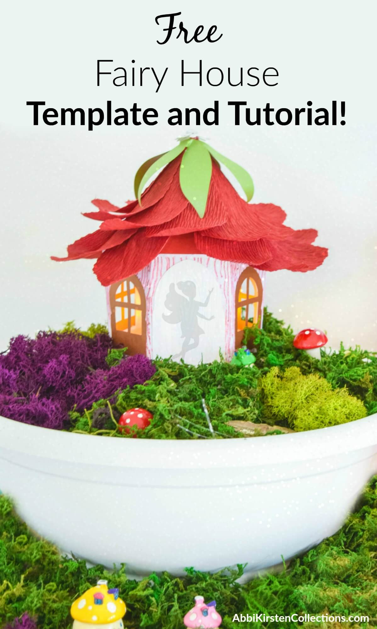 A paper fairy house sits on a bed of faux moss in a white bowl. The house has a silhouette of a fairy in the doorway and a roof made of red crepe paper flower petals, as if the house had a flower for a roof. You can make this craft using Abbi Kirsten's free fairy house template. 