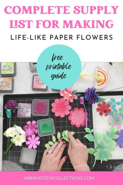 The image shows a craft table with a women making handmade paper flowers using her Cricut machine, scissors and other paper flower supplies