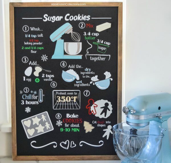 A blackboard Christmas recipe sign with colorful baking images and text describing sugar cookies.