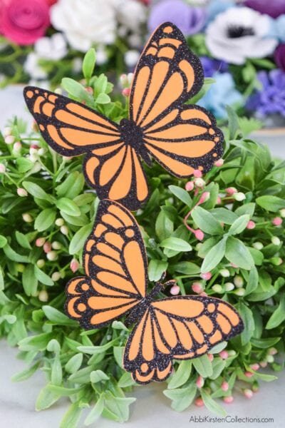 Paper Monarch butterflies are delicately placed on faux greenery to  make a wonderful table decoration. 