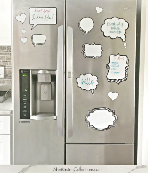 A stainless steel refrigerator with numerous white and black speech bubbles and shapes, some with colorful handwritten messages.