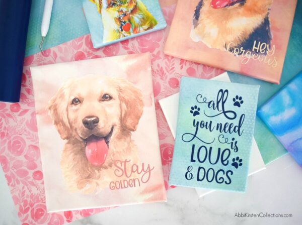 An array of cards featuring watercolors of Abbi's dogs, with the graphic saying "All you need is love and dogs" and "stay gorgeous." There is no limit to the gifts you can make with a Cricut machine and printable vinyl. 