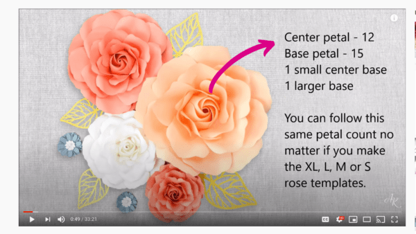 A picture taken from a paper flower tutorial on YouTube. Orange, white and yellow paper flowers adorn a table while the instructions for determining petal count are written down the side. 