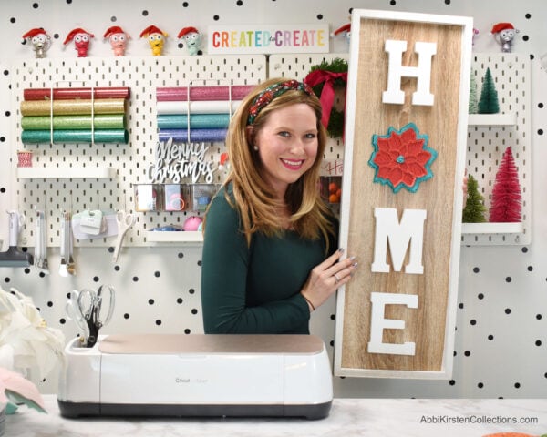 Abbi poses with her home sign craft. Use the mandala from the poinsettia mandala Christmas cards template as the “O” in a wooden sign to spell “home”.