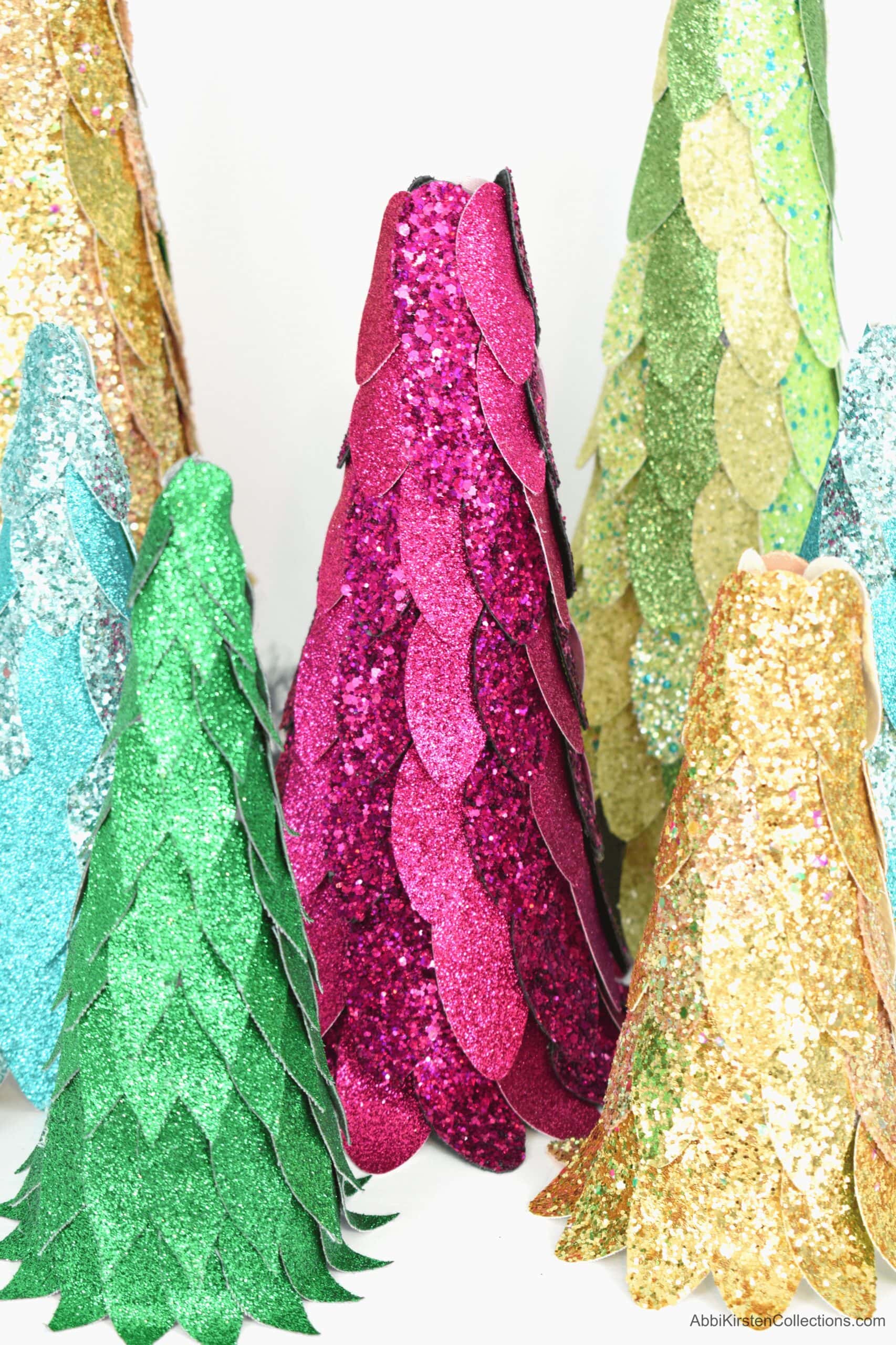 A close-up image of six completed faux leather glittery Christmas trees, each a different height and color. These leather Christmas trees are an easy Christmas decor DIY for your home!