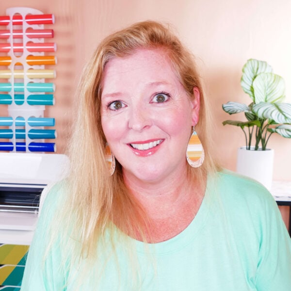 Amy Romeu wearing a seafoam green shirt and yellow and white striped earrings.