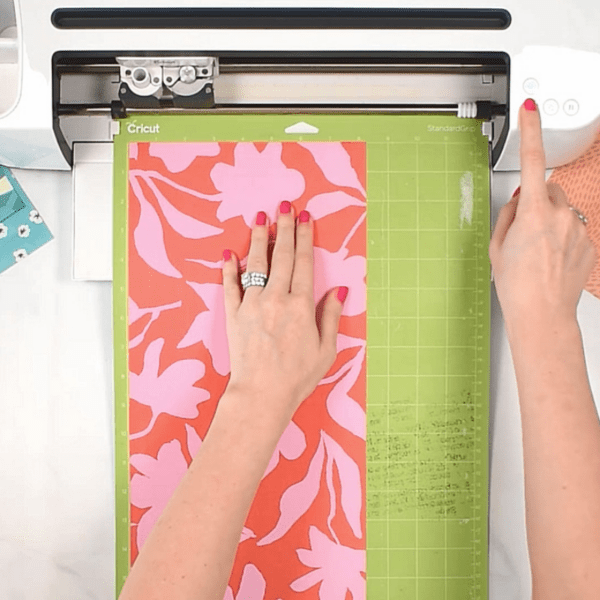 A Cricut cutting red and pink wrapping paper. 