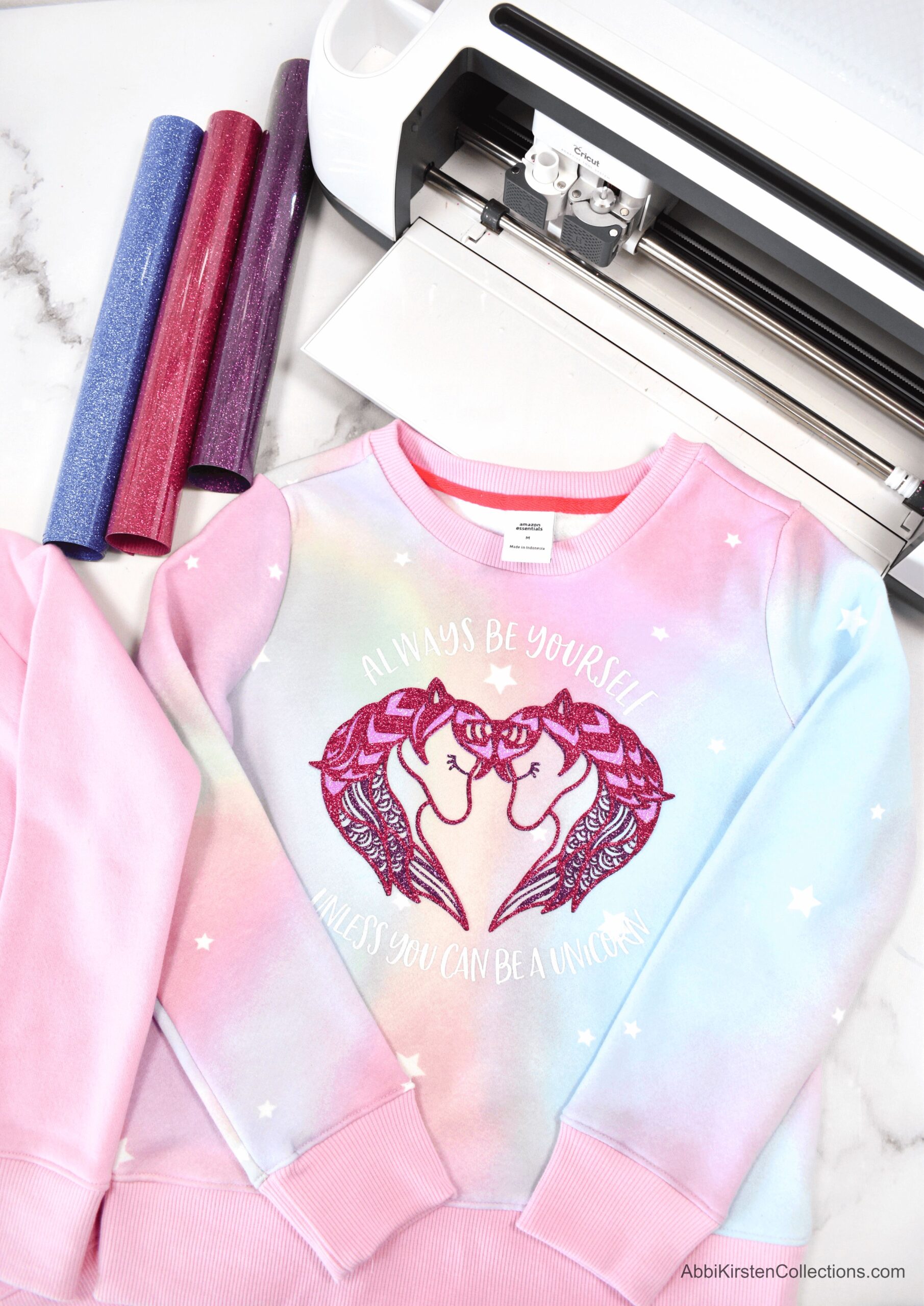 A pink and blue ombre long sleeve top with two unicorn heads forming a heart shape print