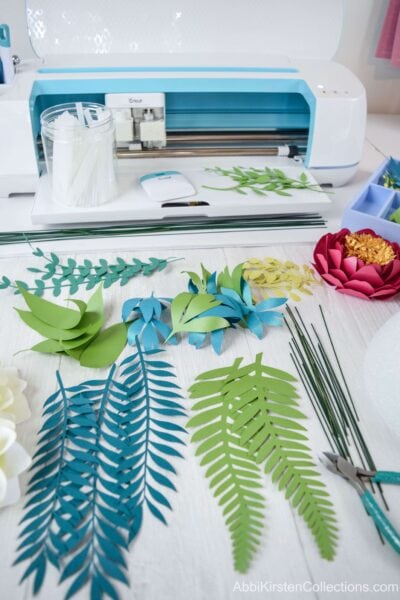 A closer look at ferns, vines, and leaves made of paper and the wire and pre-assembled flowers needed to make a paper flower bouquet.