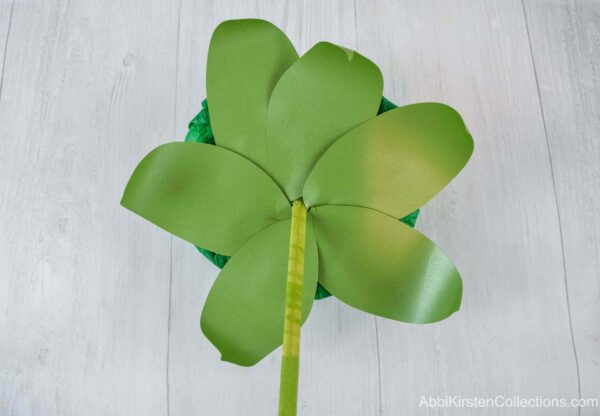 Curled green paper leaves are added to the bouquet base above the cascading paper flower bouquet handle. 